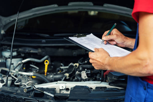 Mechanic taking notes in front of a car engine

